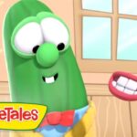 Green cucumber character with big eyes and a red bow tie smiles in a cartoon room; VeggieTales logo in the corner.