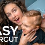Woman giving a haircut to a smiling young boy; scissors in hand, cozy home setting, with bold white text 'EASY HAIRCUT' on the image