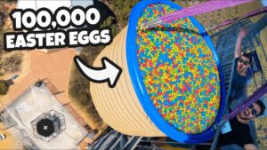 Aerial view of a blue tub full of colorful Easter eggs on a platform, with two excited men nearby and a bold '100,000 Easter Eggs' banner text.