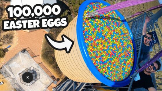 Aerial view of a blue tub full of colorful Easter eggs on a platform, with two excited men nearby and a bold '100,000 Easter Eggs' banner text.
