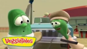 Two VeggieTales vegetables talk to each other in a kitchen, with a blender behind them and a hand holding a spatula nearby.