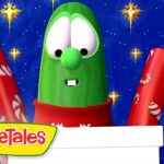 Larry the Cucumber from VeggieTales wearing a red scarf, with two red gift tubes against a blue starry background, logo bottom left.