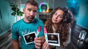 Couple sits in a bright home, showing ultrasound photos and pink markers to the camera with puzzled expressions.