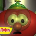 Red tomato character from VeggieTales with wide eyes and open mouth, in a lab-like setting with a VeggieTales logo visible.