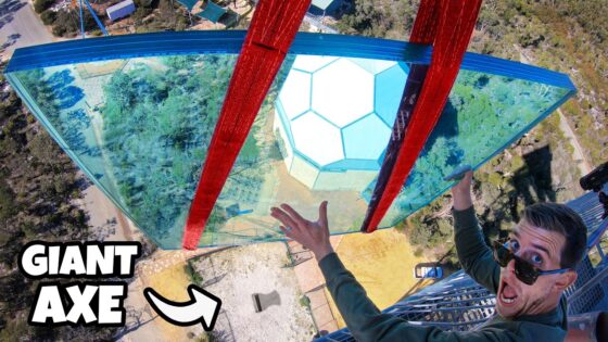 YouTube thumbnail showing a man in sunglasses on a glass walkway high above ground, with a large red axe between the glass panels and bold 'GIANT AXE' text in the corner.
