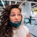 Woman with a teal mask pulled down under her chin stands at a store checkout area inside IKEA.