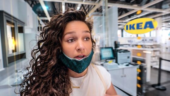 Woman with a teal mask pulled down under her chin stands at a store checkout area inside IKEA.