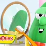 Larry the Cucumber from VeggieTales brushing teeth with an orange toothbrush in front of a round mirror.