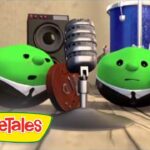 Two green VeggieTales characters perform on a wooden stage with a mic and guitar; VeggieTales logo in the corner.