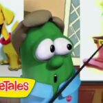 Green VeggieTales host with a pointer, shown with a split-screen slide of a dog on the left and a hat-wearing green veggie on the right.