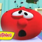 Close-up of a surprised red tomato character from VeggieTales, with wide eyes and open mouth in a colorful set.