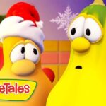 Two VeggieTales characters, one in a Santa hat, stand in a colorful room with the VeggieTales logo in the corner.