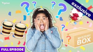 Surprised girl in a denim jacket with confetti, question marks, drums, and a mystery box in a bright thumbnail. The scene suggests surprising contents or an exclusive reveal.