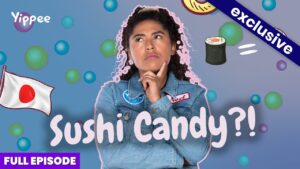 Thoughtful woman in a denim jacket surrounded by candy bubbles, sushi icon, and Japan flag; YouTube thumbnail for 'Sushi Candy?!' exclusive full episode.