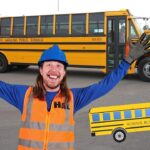 Happy worker in a blue hard hat and orange safety vest raises arms in a bus yard with yellow school buses; cartoon school bus graphic overlays the foreground.