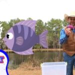 Cowboy wearing a hat and vest at a lake, holding a pink lure with a cartoon fish and ‘COWBOY JACK’ overlay.
