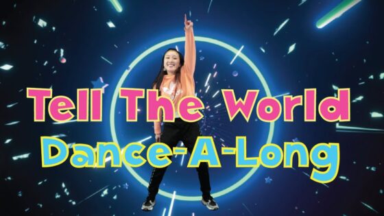 Intro slide for a dance-along video featuring a girl dancing in front of a neon ring and bold pink and blue text: 'Tell The World Dance-A-Long'.