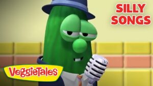 Larry the Cucumber from VeggieTales wearing a hat and suit, singing into a vintage microphone with 'Silly Songs' title in the corner.