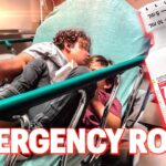 Two children lie on a hospital emergency room stretcher, bundled in a green sheet, with a large cherry Tylenol bottle graphic and the bold 'EMERGENCY ROOM' text overlay in the foreground.