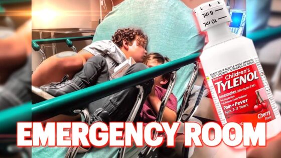 Two children lie on a hospital emergency room stretcher, bundled in a green sheet, with a large cherry Tylenol bottle graphic and the bold 'EMERGENCY ROOM' text overlay in the foreground.