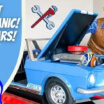 Friendly cowboy in a plaid shirt and hat leans over a blue toy car with its hood open, set up like a mechanic workshop for a kids’ video.