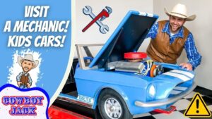 Friendly cowboy in a plaid shirt and hat leans over a blue toy car with its hood open, set up like a mechanic workshop for a kids’ video.