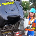 Worker in blue hard hat and orange vest near an overturned dumpster on a truck, with a cartoon truck graphic nearby and bold 'AWESOME TRUCKS!' text overlay.