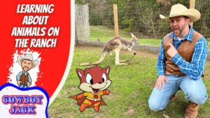 Man in cowboy hat and vest kneels on grass, pointing at a cartoon fox superhero and a real kangaroo near a fenced pen on a ranch set.