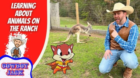 Man in cowboy hat and vest kneels on grass, pointing at a cartoon fox superhero and a real kangaroo near a fenced pen on a ranch set.