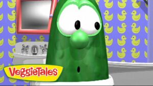 Green veggie character in a bathroom set from VeggieTales, with yellow duck wallpaper and a sink, logo in the corner.