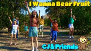 Group of diverse kids in an orange orchard, waving happily; title reads 'I Wanna Bear Fruit' and 'CJ & Friends' with a cartoon monkey.
