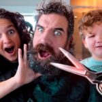 A bearded man with surprised expressions, flanked by a woman and a child, as a pair of scissors hovers near his beard in a playful scene.
