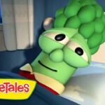 Green VeggieTales character lying in bed with a sleepy expression.