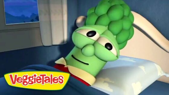 Green VeggieTales character lying in bed with a sleepy expression.