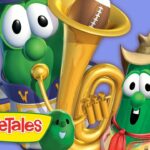 Two VeggieTales characters pose with a large golden brass instrument and the VeggieTales logo visible in bright colors.