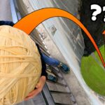 Person at a high ledge holding a giant skein of yarn, eyes wide in surprise, with an orange arc pointing to a distant green valley below.