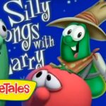 VeggieTales scene with green cucumber characters; one wears a hat and plays a banjo, others look on; text reads Silly Songs with Larry on a blue background with VeggieTales logo.