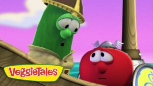 Green cucumber character wearing a hat leans toward a red tomato aboard a wooden ship, with a pink-purple sky and VeggieTales logo in the corner.