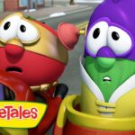 Two colorful VeggieTales characters in a red car, looking surprised as they drive on a city street, with the VeggieTales logo in the corner.