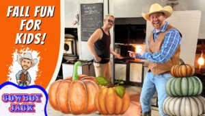 Two men in a blacksmith shop pose by a glowing forge; foreground pumpkins and a bright orange banner that says 'Fall Fun for Kids!' with a cartoon cowboy and 'Cowboy Jack' logo on the left.