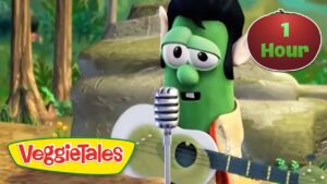 Green VeggieTales character (Larry the Cucumber) sings into a microphone while strumming a guitar; VeggieTales logo visible in the corner.