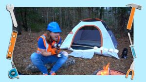 Man in a blue hard hat and orange safety vest sits by a small camping tent in a forest, holding a cordless drill.