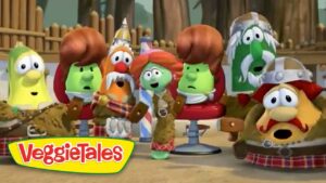 Group of VeggieTales characters seated in a theater audience, watching a performance, colorful veggies with curious expressions, VeggieTales logo visible in the corner.