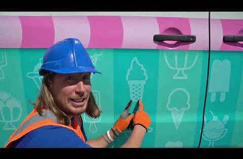 Person wearing a blue hard hat and orange safety vest applying an ice-cream themed vinyl wrap to a teal van with a pink stripe.