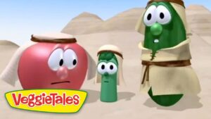 Three VeggieTales characters in desert robes stand with worried expressions, sandy dunes and pyramids in the background.