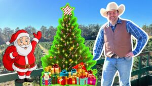 Cartoon Santa waving beside a decorated Christmas tree and colorful wrapped gifts, with a smiling cowboy standing on a sunny outdoor balcony.