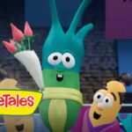 Green veggie character holding a bouquet of pink roses on stage, VeggieTales logo visible in foreground, smiling audience of veggies nearby.