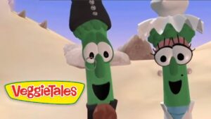 Two green beans with expressive faces wearing clothes stand in a sandy desert, VeggieTales logo visible in the corner.