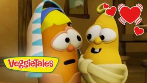 Two VeggieTales characters share a hug, smiling as red hearts surround them, logo at bottom left.