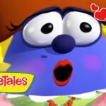 Blue VeggieTales character with a surprised expression, blush on cheeks, logo 'VeggieTales' bottom left, and hearts in the corner.
